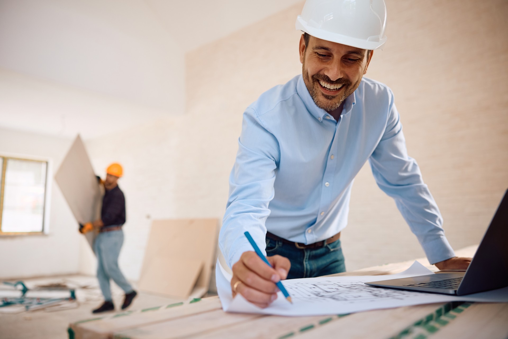 Happy architect analyzing housing plans during home remodeling project.